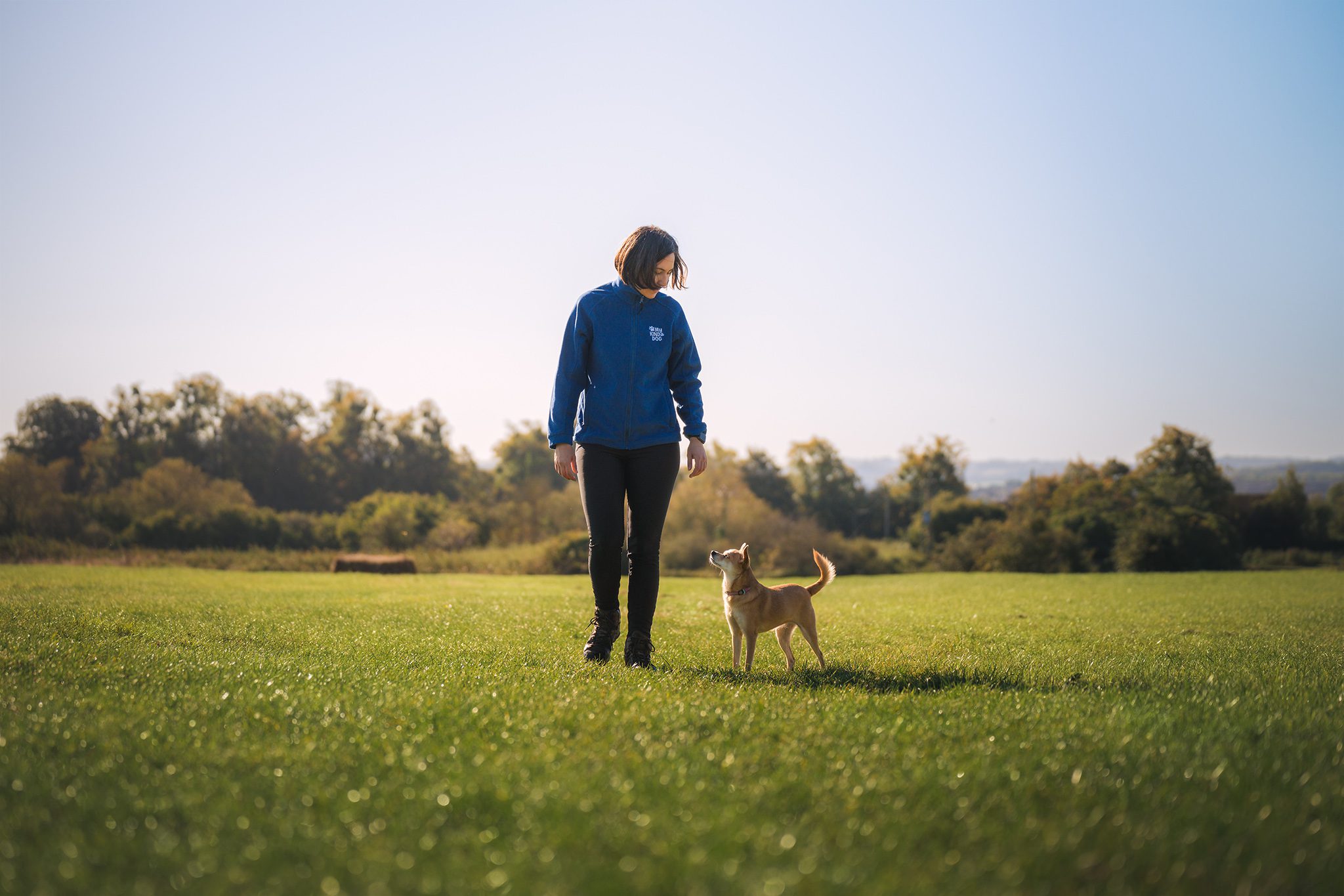 Bristol dog trainer and behaviourist demonstrating loose lead walking techniques with her dog off lead during an outdoor training session.